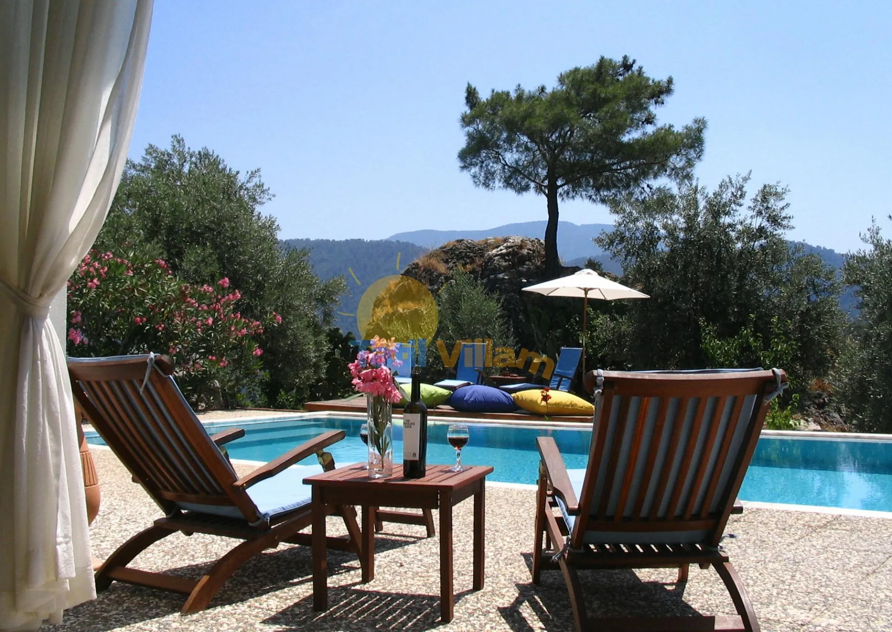 La zona de estar junto a la piscina da a una piscina y colinas lejanas.