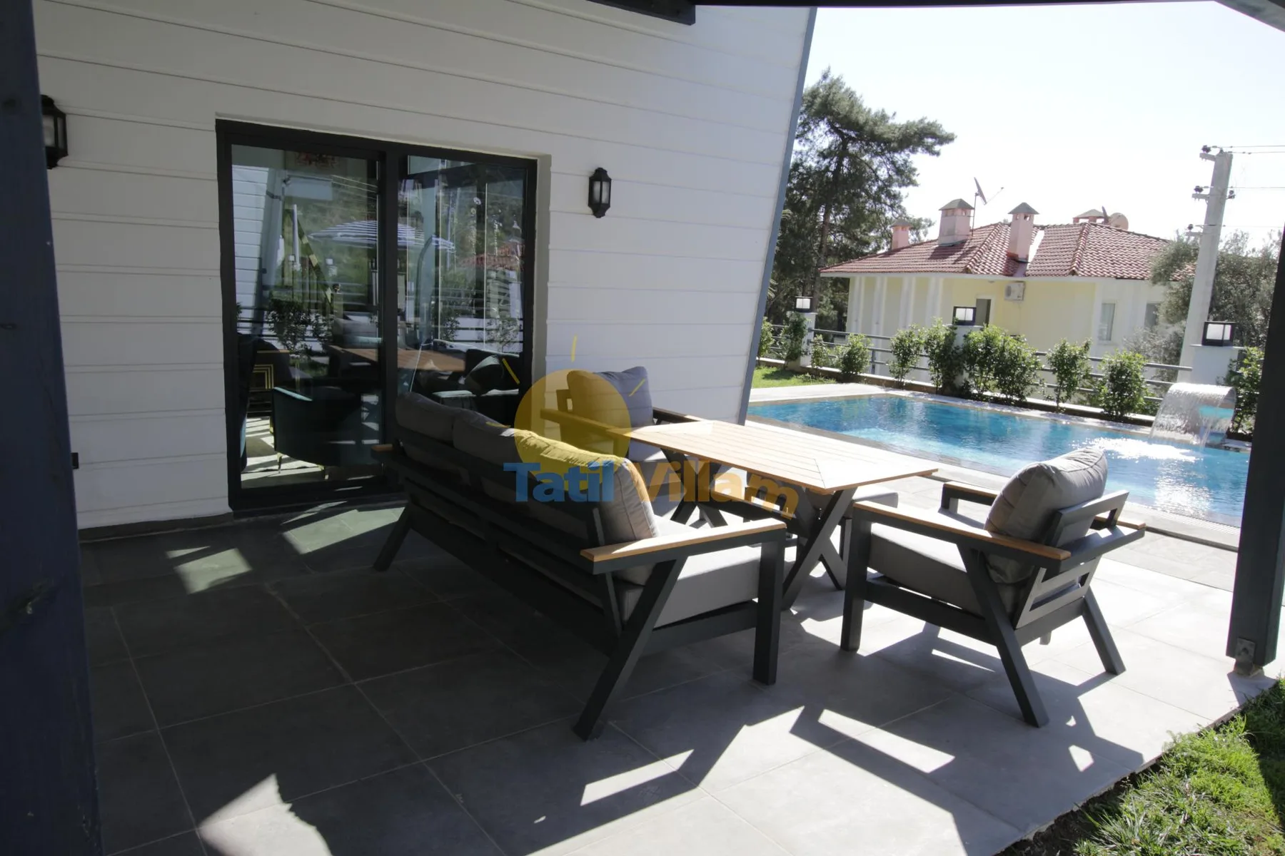 Una zona de comedor en el patio con asientos exteriores da a una piscina.