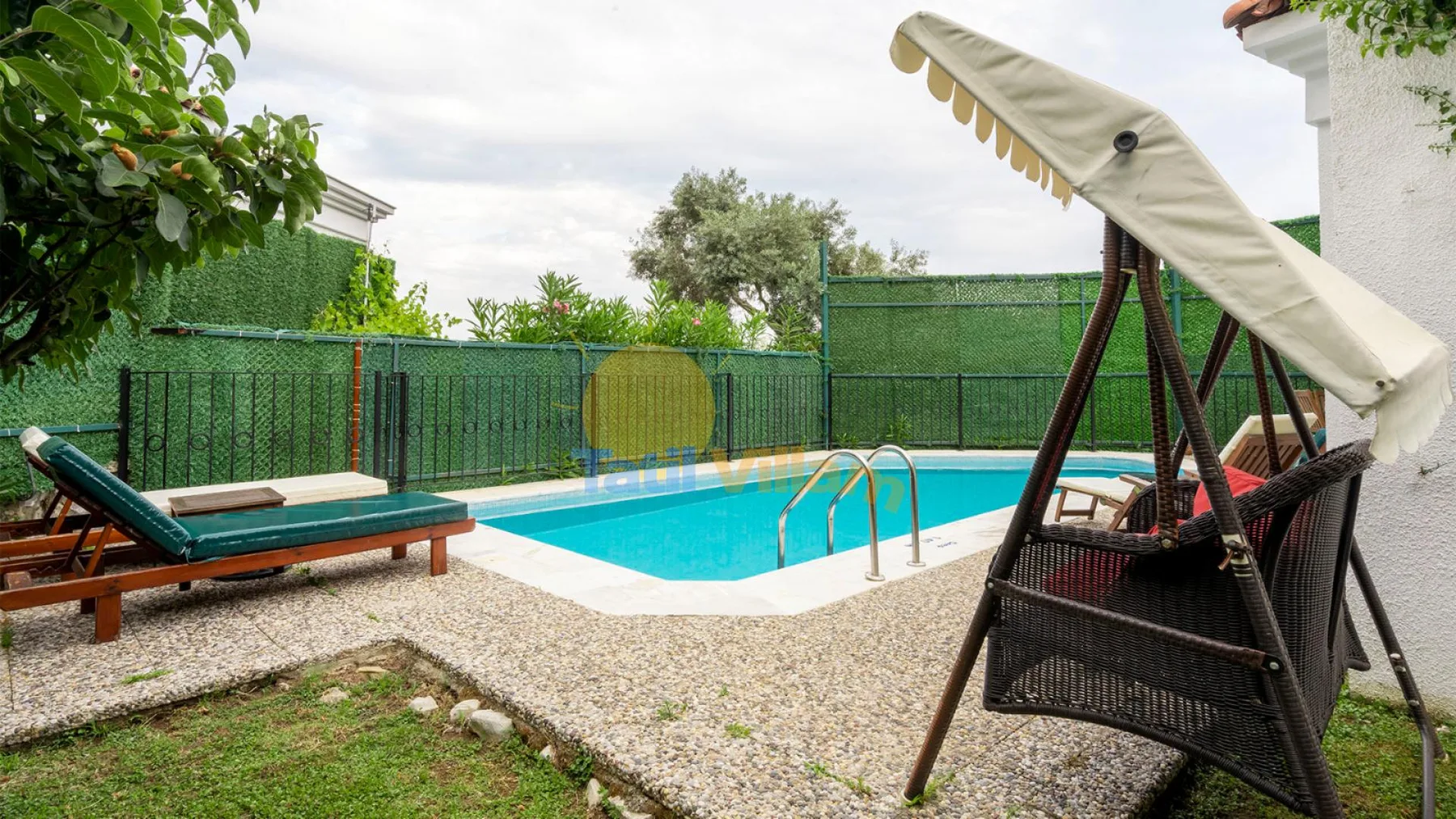 Una piscina al aire libre con una escalera y un columpio cubierto cerca.