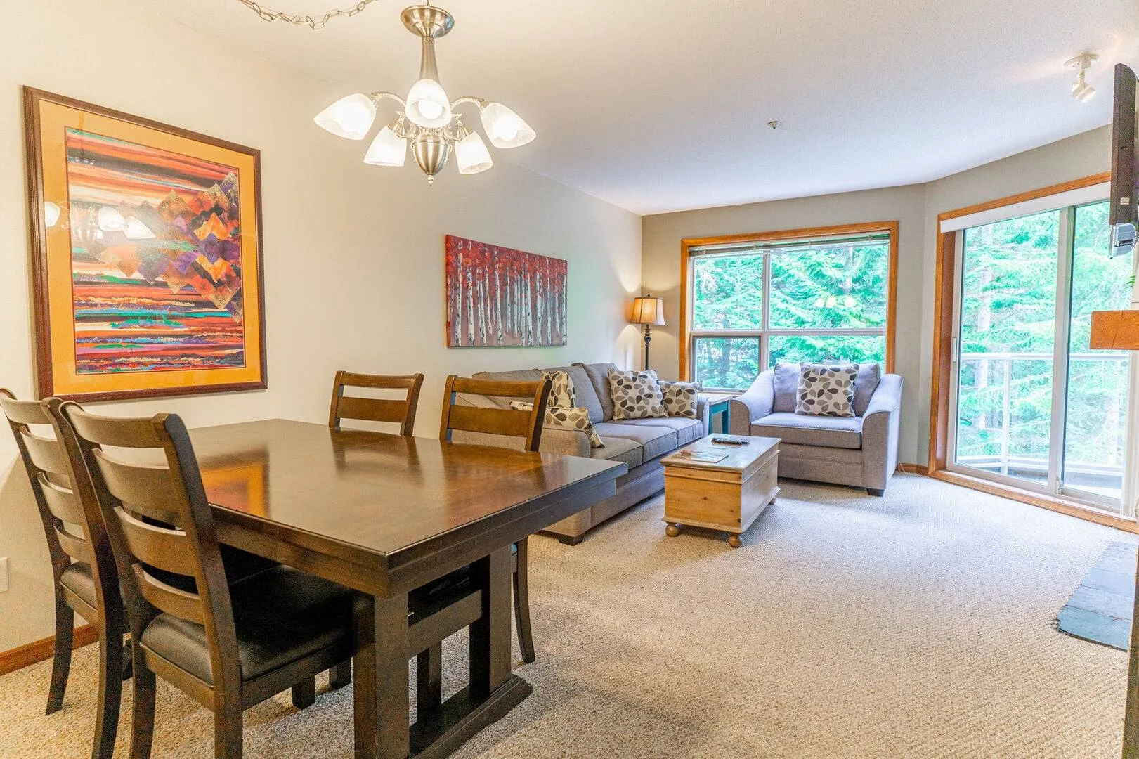 A living and dining area with a table, seating, and large windows.
