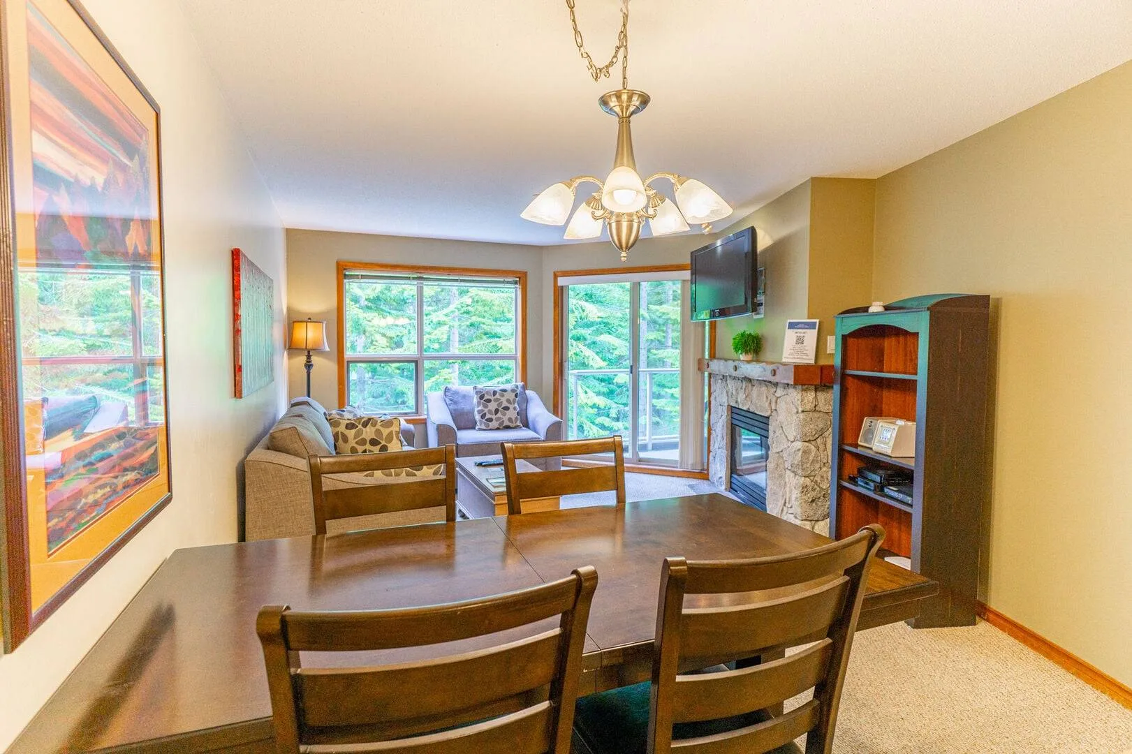 A living room with a dining table, seating, and large windows.