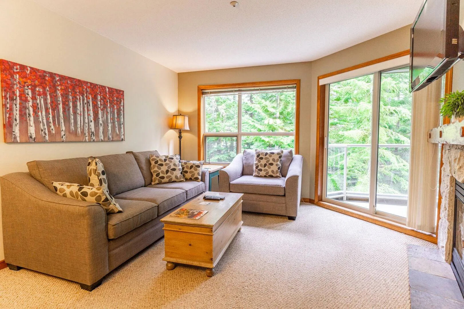 A living room with seating, a coffee table, and large windows.