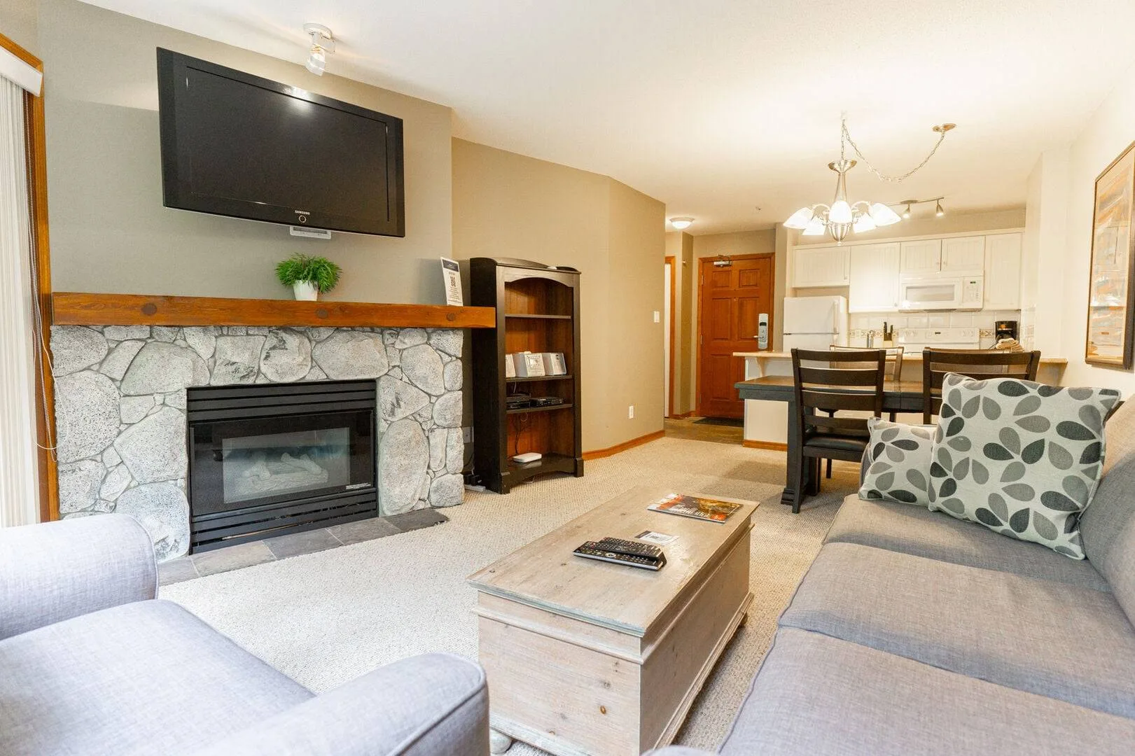 A living room with a stone fireplace, seating, and an open dining area.