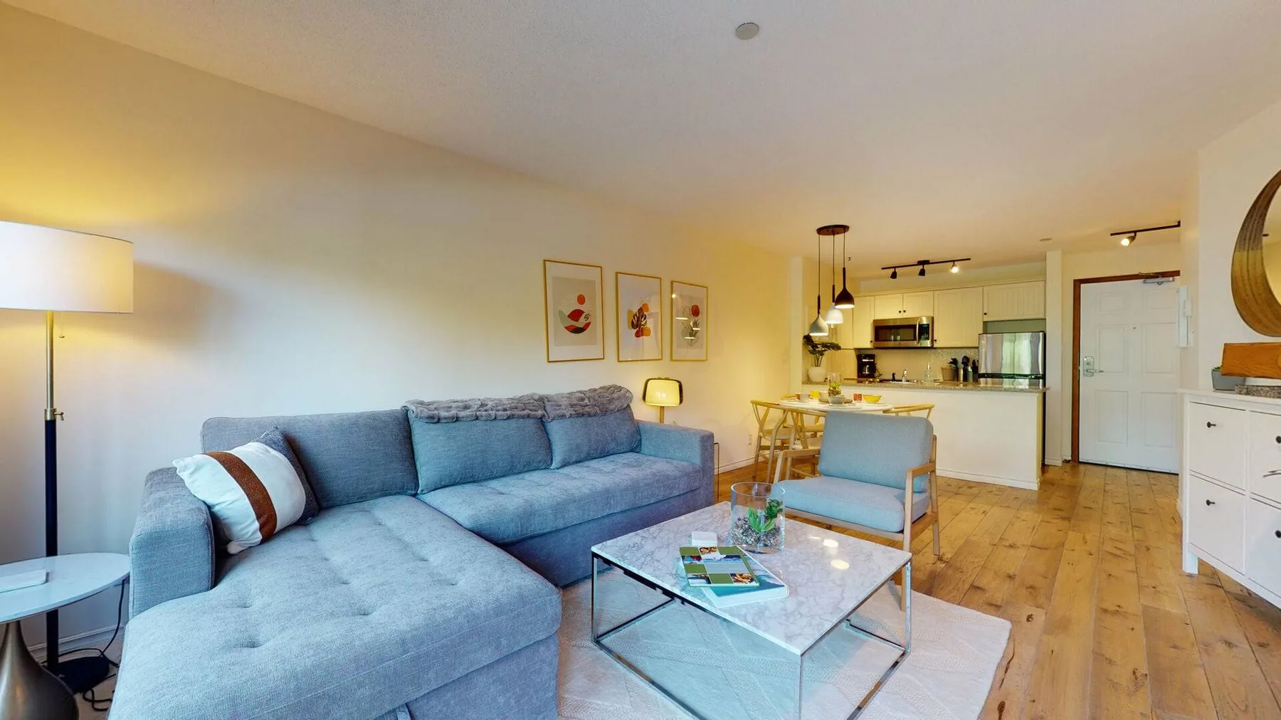 A living area with a blue sectional, coffee table, and open kitchen.