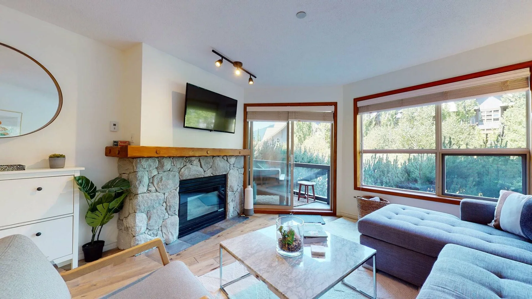 A bright living room with a stone fireplace and large windows.