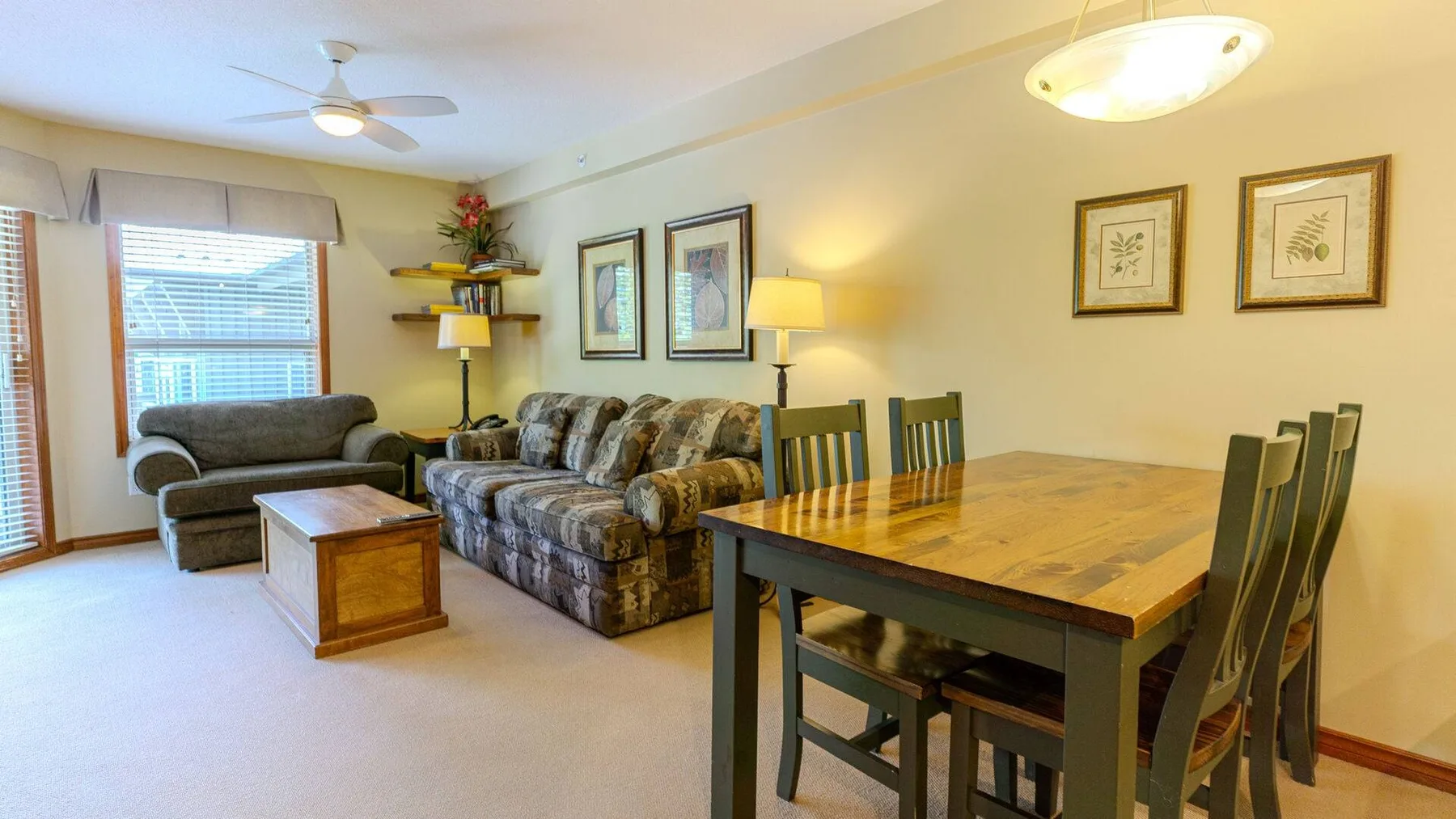 A carpeted living and dining room with seating and a wooden dining table.