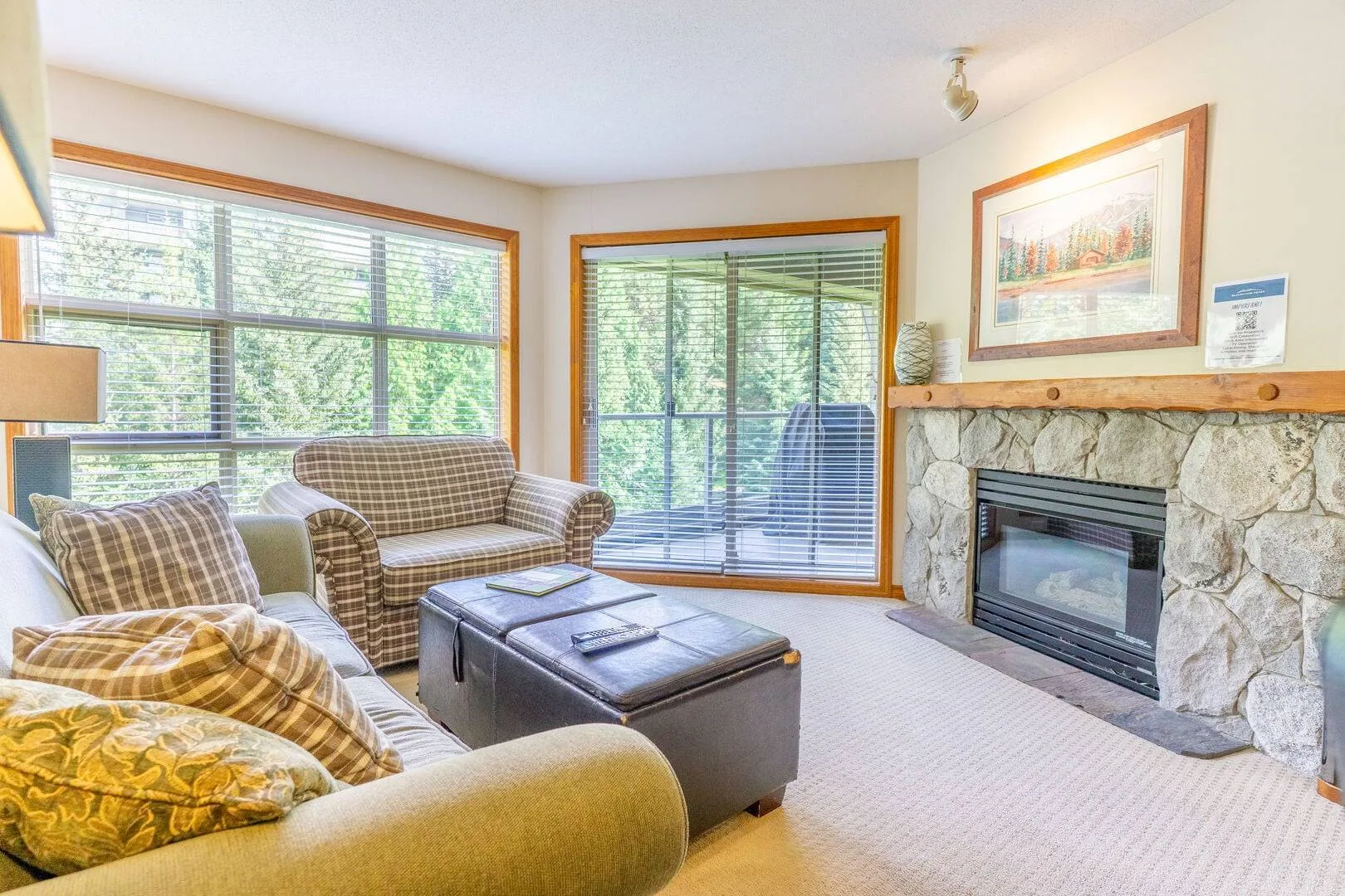 A living room with seating arranged around a coffee table beside a stone fireplace.