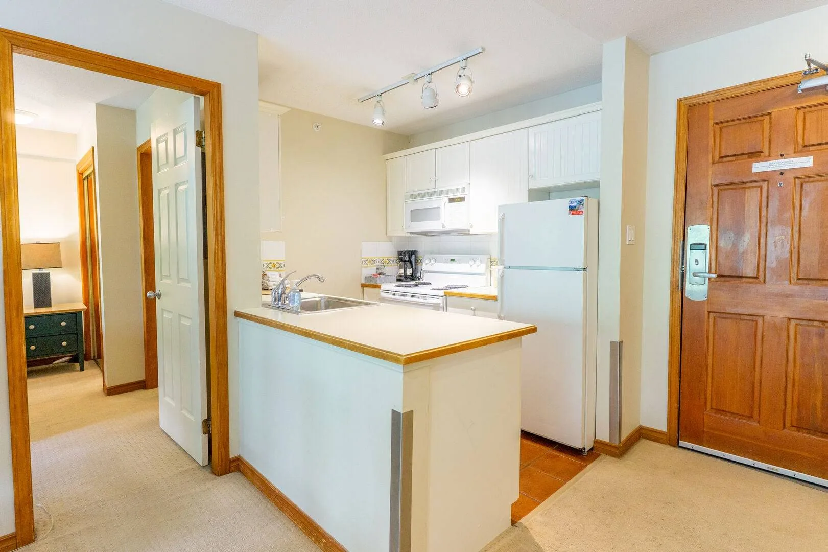 A kitchen with a central counter, white cabinets, and a refrigerator.