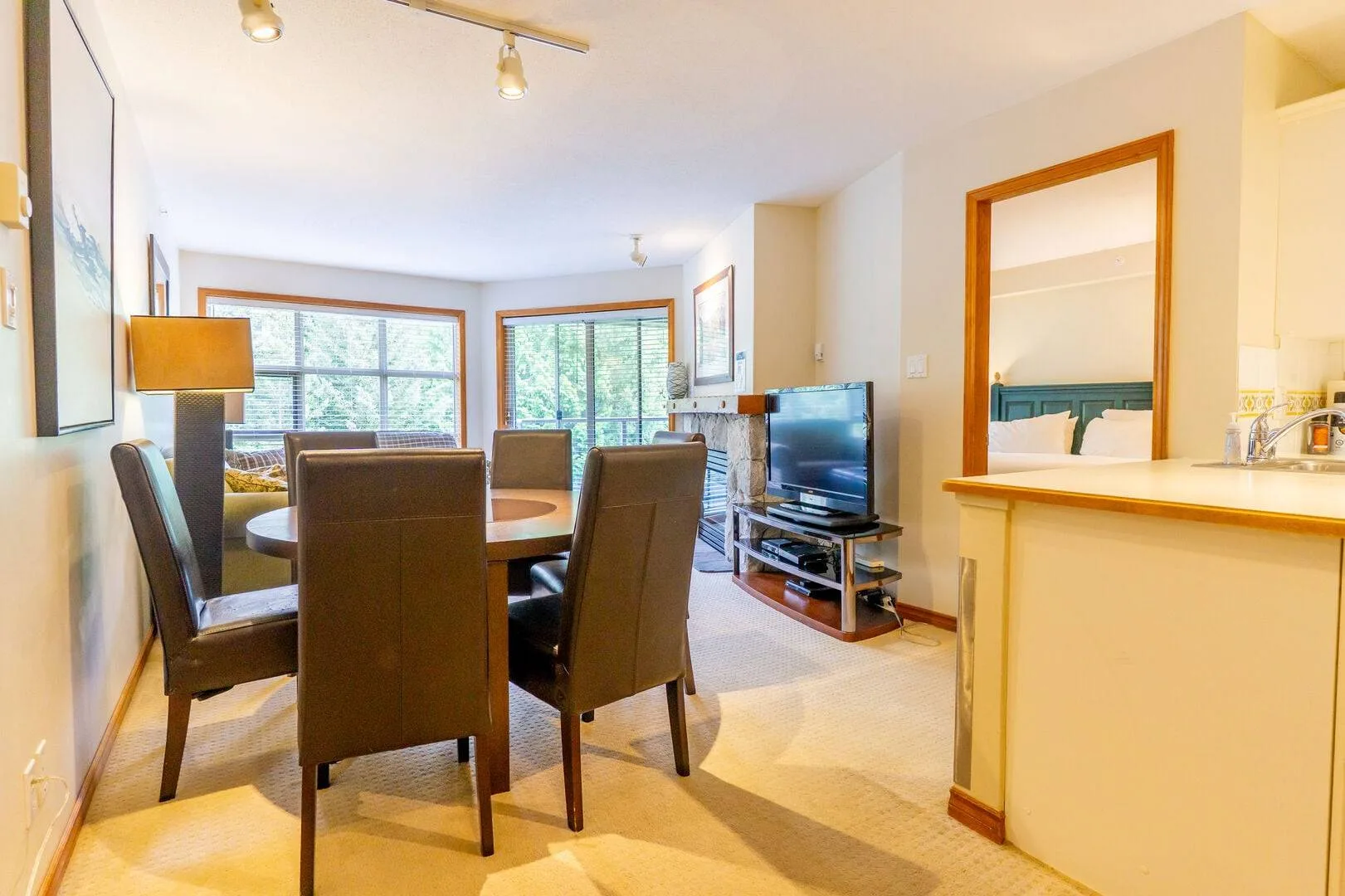 A dining and living area with a table, seating, and a television.