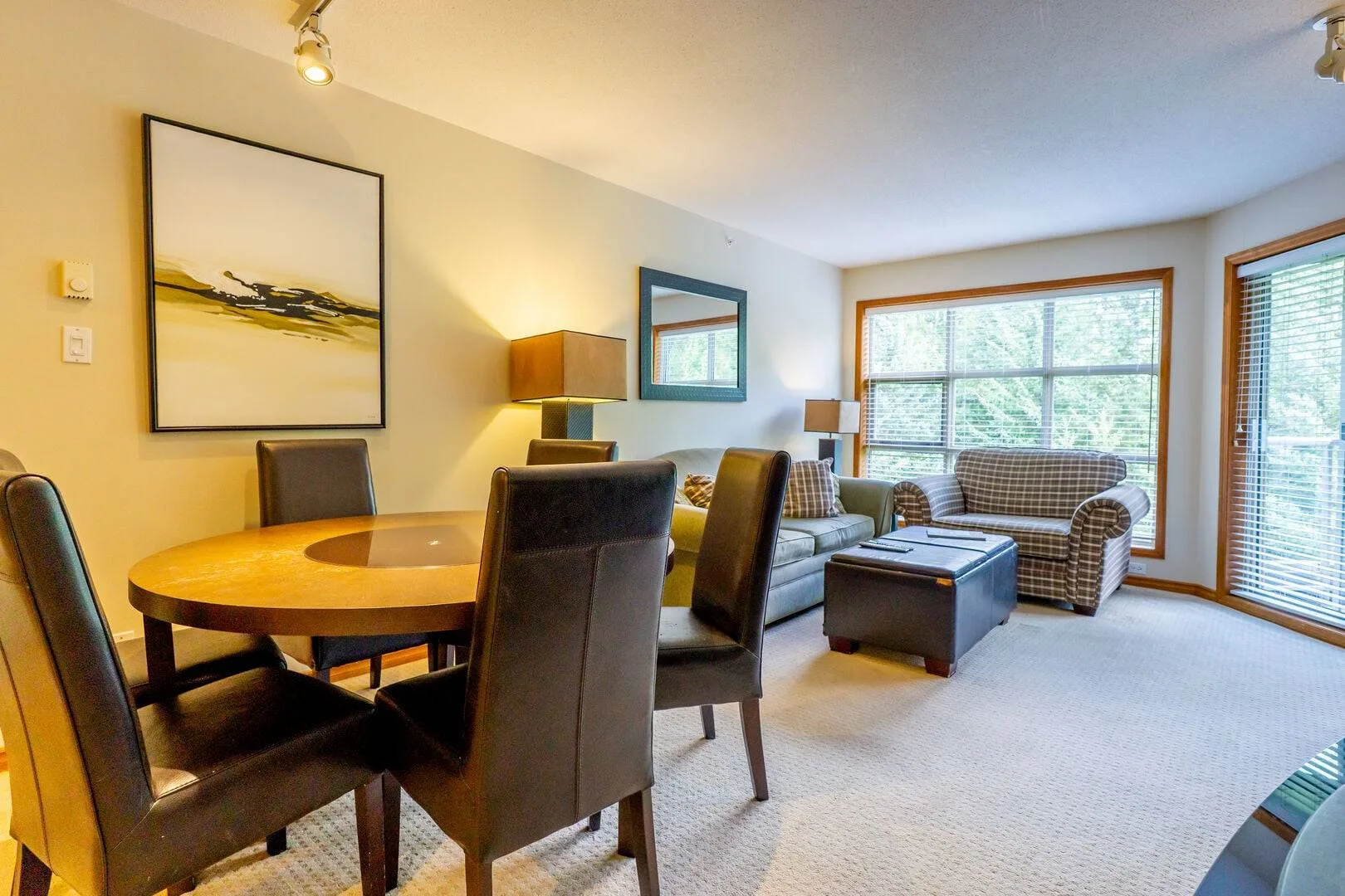 A living room with seating around a coffee table and a dining table nearby.