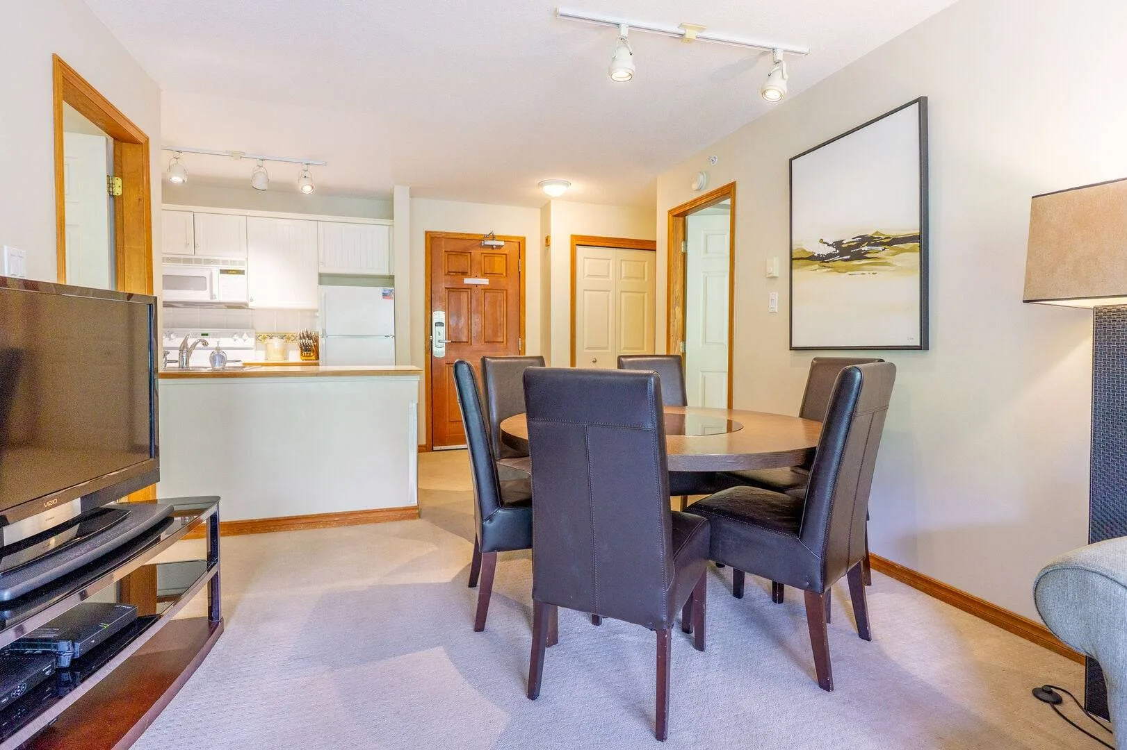 A dining area with a round table and upholstered seating beside an open kitchen.