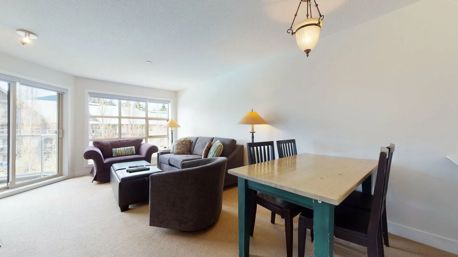 A bright living and dining area with seating beside a wooden dining table.