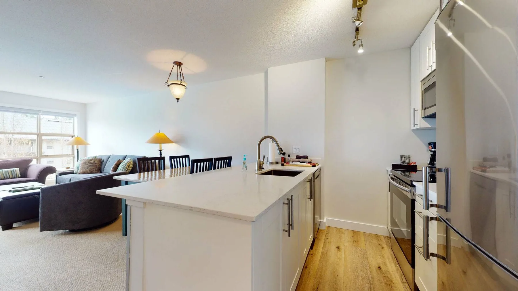 A bright kitchen with a large island and an adjoining living area.