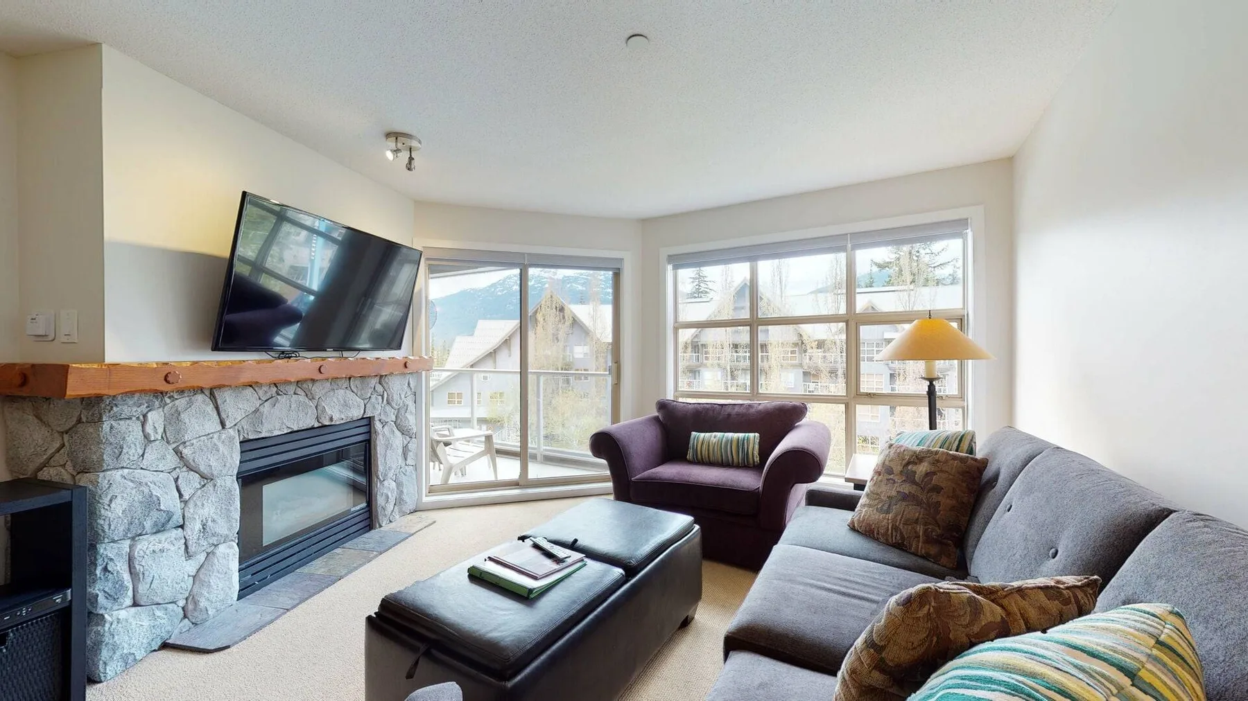 A bright living room with large windows, a fireplace, and seating.