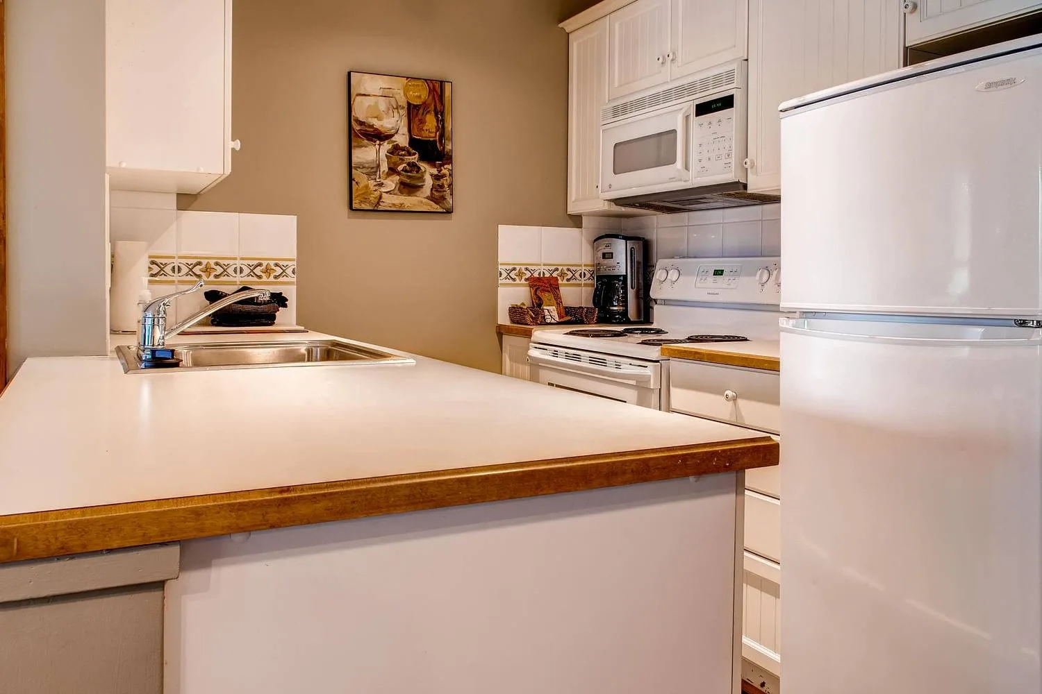 A kitchen with a broad counter, sink, and appliances.