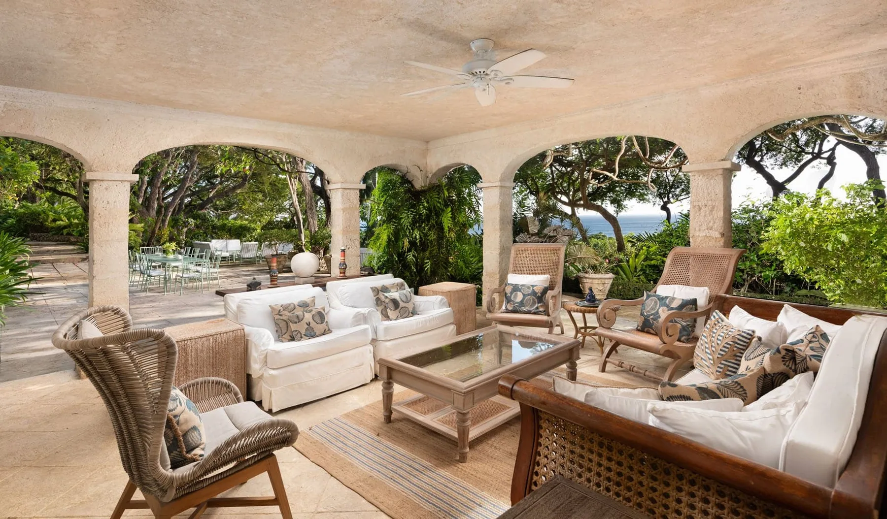 A covered outdoor lounge with cushioned seating and a wooden coffee table.