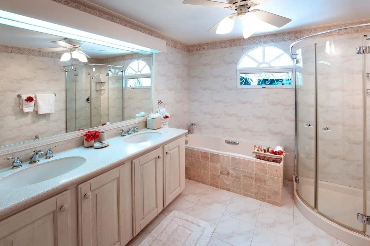 Un baño amplio con un tocador largo, bañera y ducha de vidrio.