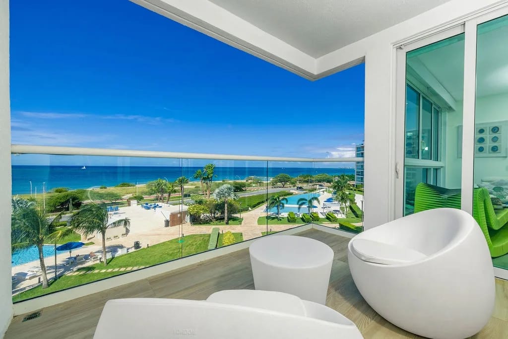 Relax in your private balcony with stunning sea views, where turquoise waters meet lush tropical gardens and sparkling pools below—your perfect retreat awaits.