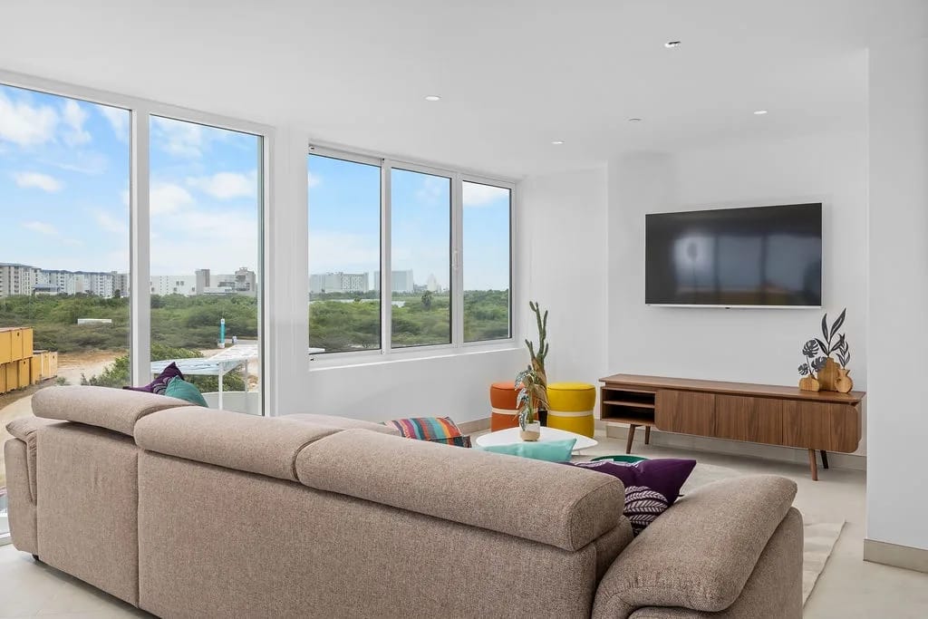 Sala de estar con un cómodo sofá seccional y ventanas de piso a techo.