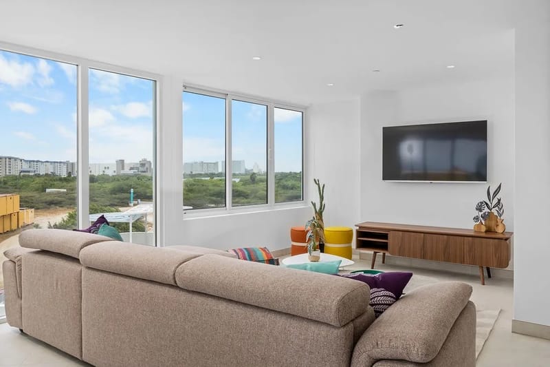Sala de estar con un cómodo sofá seccional y ventanas de piso a techo.