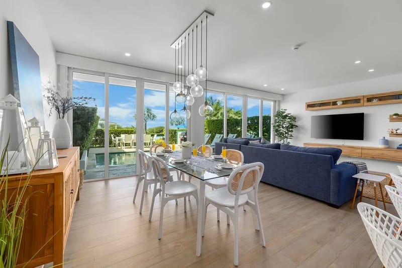 Reúnanse alrededor de su elegante mesa de comedor, con vistas panorámicas al jardín a través de ventanas de piso a techo, en este luminoso espacio de estar abierto.