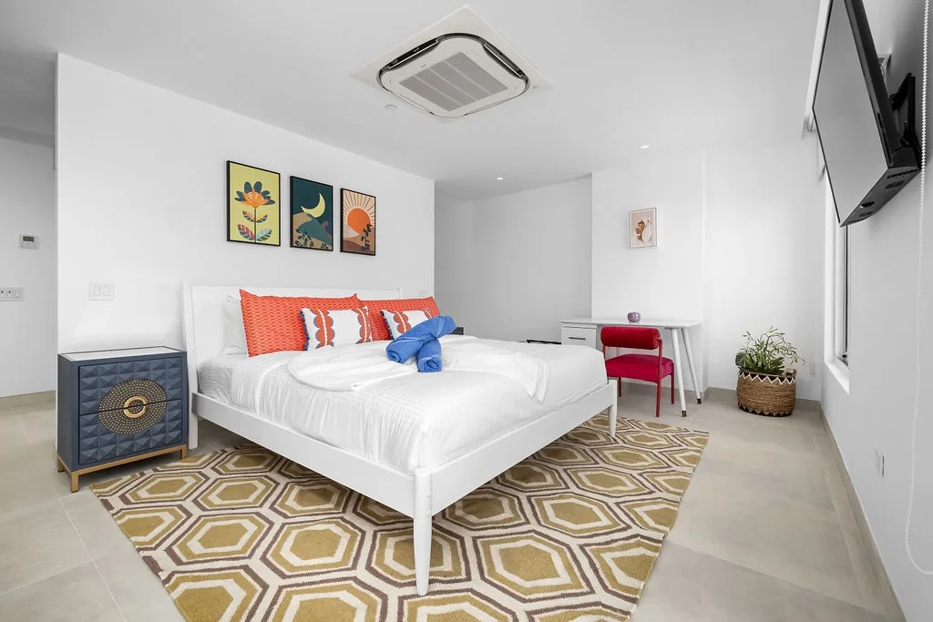 Modern bedroom with crisp white linens, colorful art, and climate control.