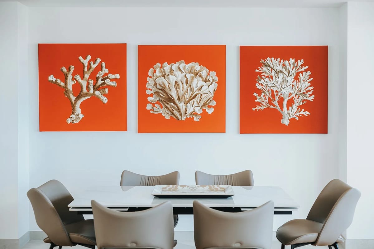 Elegante mesa de comedor debajo de una obra de arte de temática costera con corales.