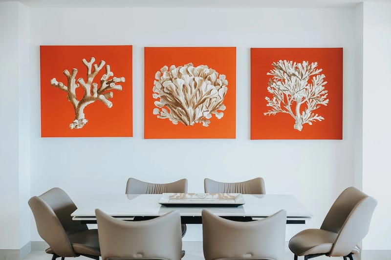 Elegante mesa de comedor debajo de una obra de arte de temática costera con corales.