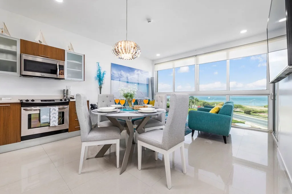 Despierta con impresionantes panorámicas del mar desde la cocina y el comedor de concepto abierto. Disfruta del café de la mañana en esta elegante mesa mientras la luz del sol entra por los amplios ventanales que revelan las aguas turquesas al otro lado.