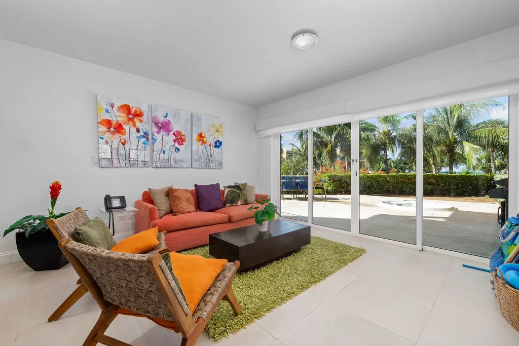 Sala de estar luminosa con colores vivos y puertas de vidrio que dan a la terraza.