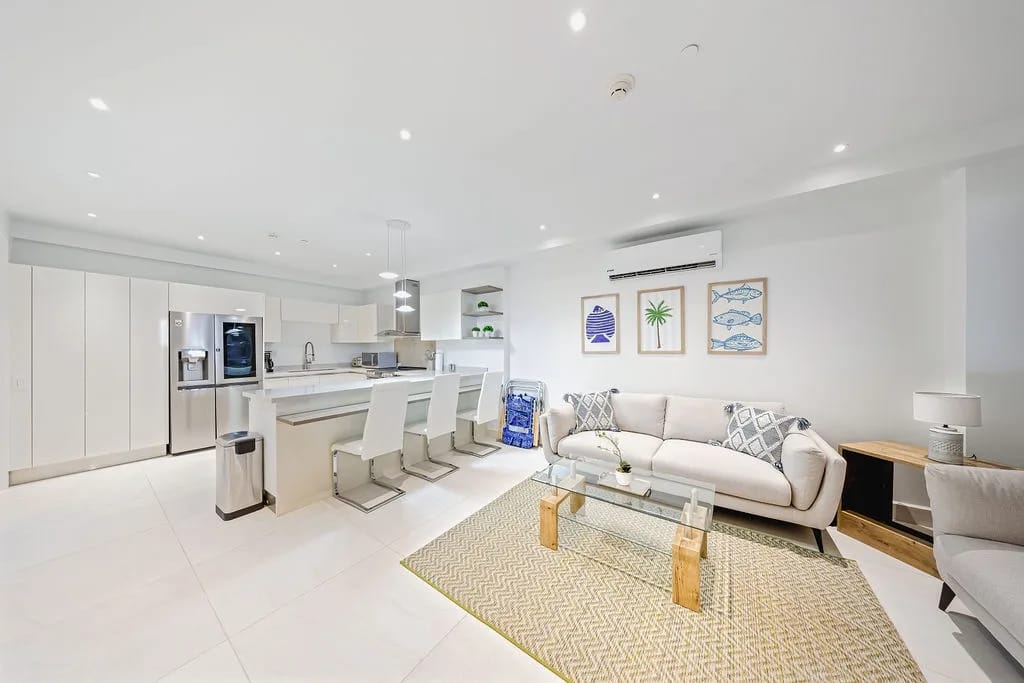 Sala de estar luminosa y abierta con un sofá mullido y una elegante cocina moderna.