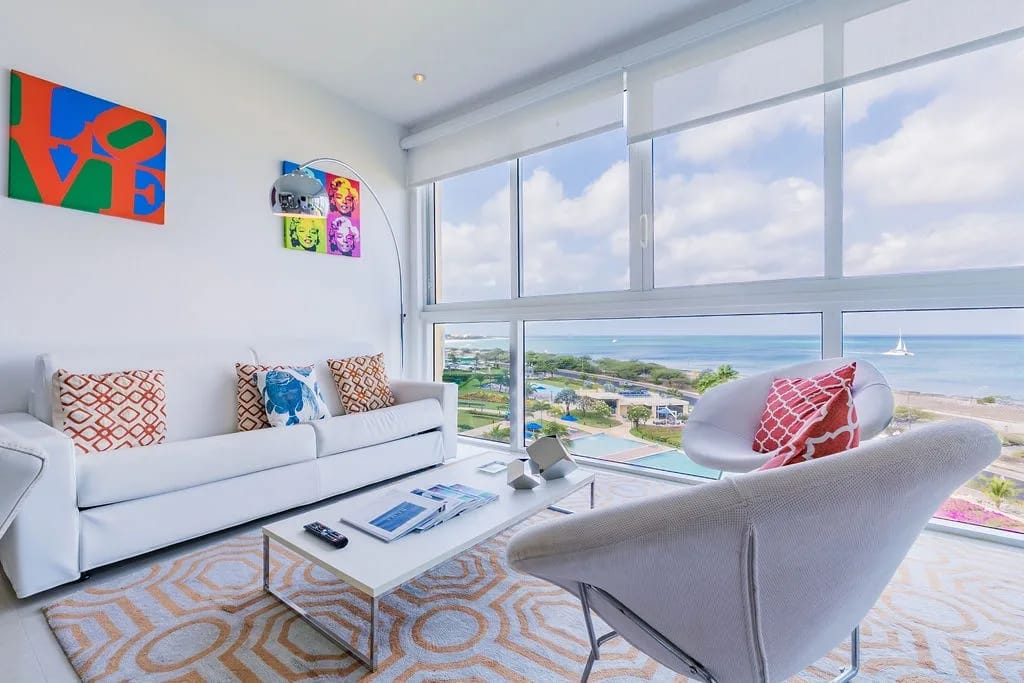 Your bright, artful living room frames stunning ocean and coastal views through floor-to-ceiling windows—perfect for relaxing on plush seating while soaking in the serene beachfront scenery.