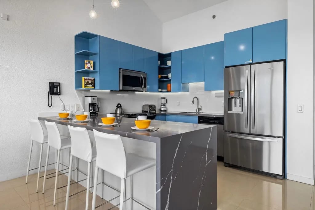 Your modern kitchen awaits with sleek stainless appliances, bold blue cabinetry, and a welcoming breakfast bar where you can gather over morning coffee and plan your day's adventures.