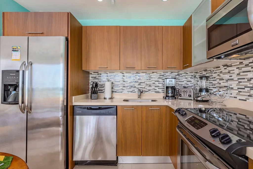 Su cocina totalmente equipada cuenta con electrodomésticos de acero inoxidable, gabinetes de madera de tonos cálidos y un elegante revestimiento de mosaico sobre la encimera, perfecto para preparar comidas en casa durante su estancia.