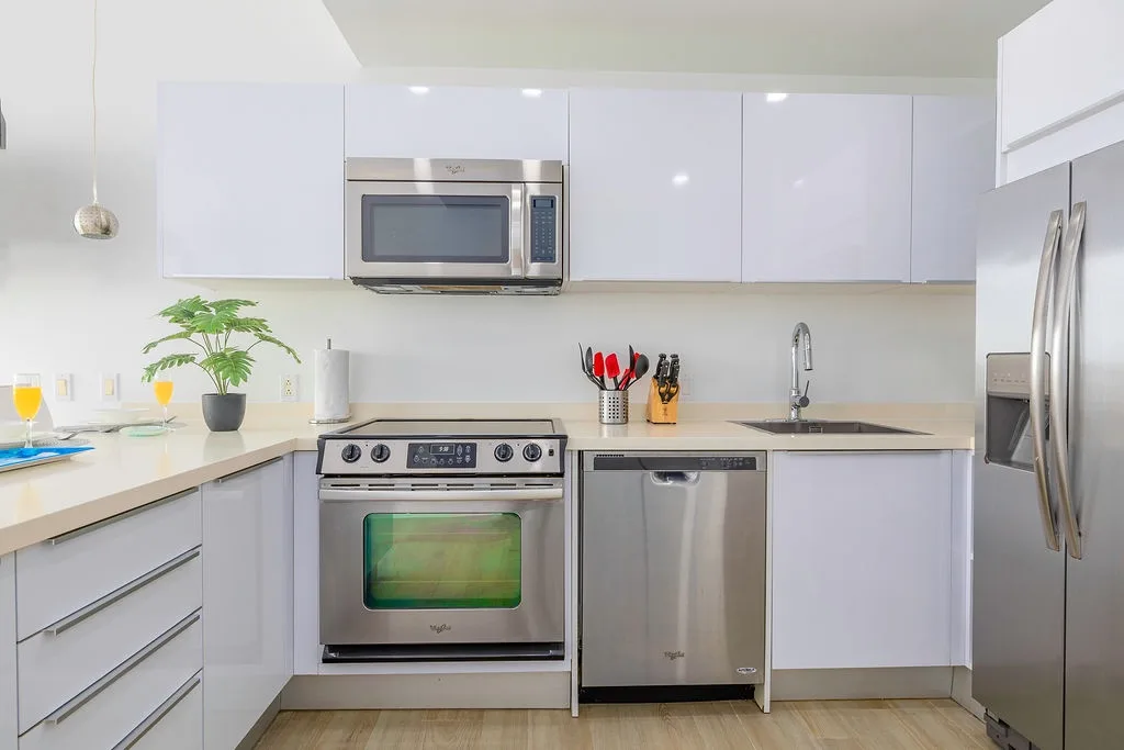 Tu cocina moderna cuenta con elegantes gabinetes blancos, electrodomésticos de acero inoxidable y todo lo que necesitas para tus aventuras culinarias.