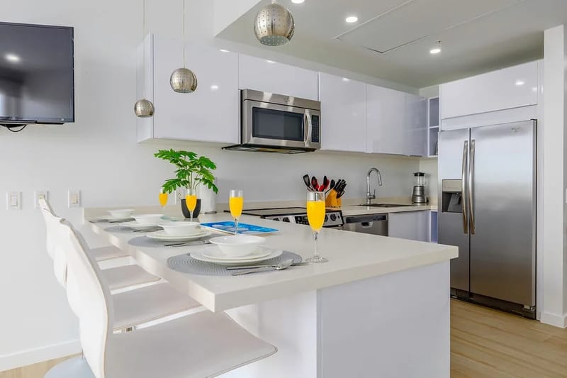 Tu elegante cocina moderna te espera con una iluminación colgante de diseño, electrodomésticos de acero inoxidable y una isla de desayuno lista para disfrutar de mimosas por la mañana.
