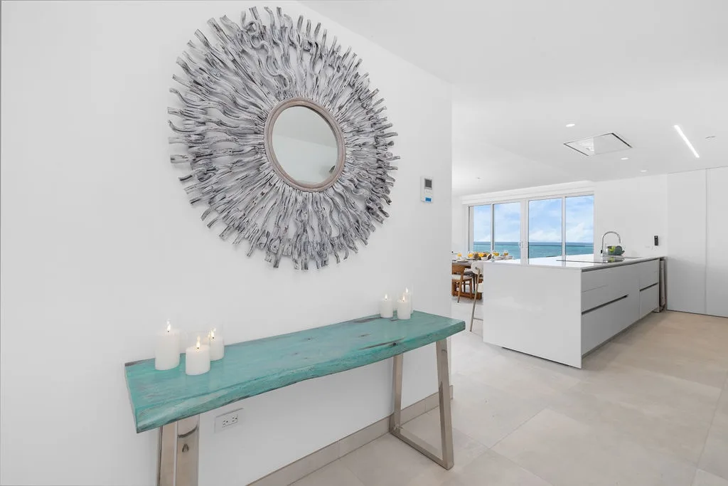 Cocina moderna de líneas elegantes con gabinetes blancos y vistas al mar a través de amplios ventanales.