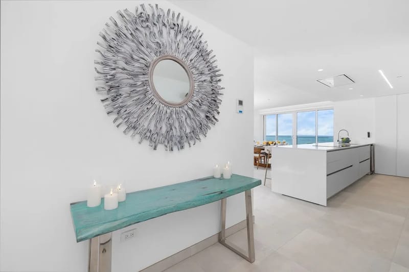 Cocina moderna de líneas elegantes con gabinetes blancos y vistas al mar a través de amplios ventanales.