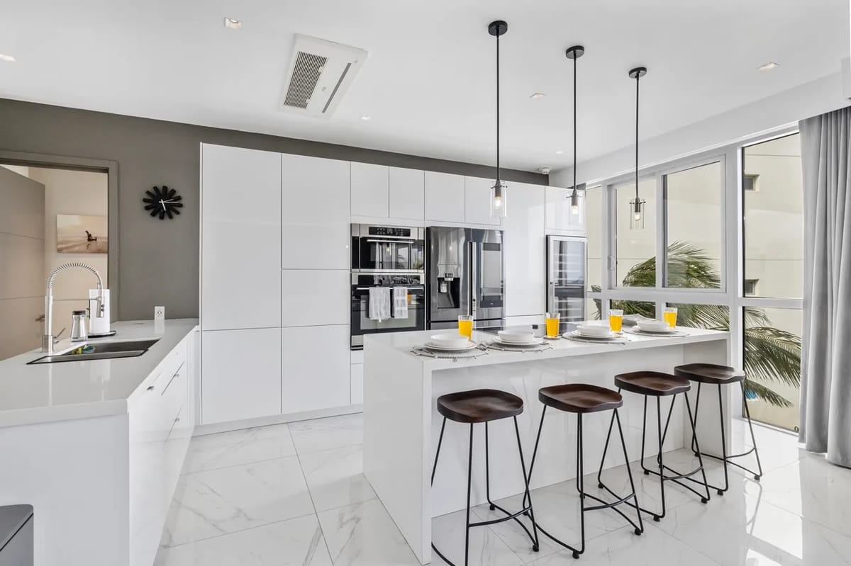 Cocina moderna con electrodomésticos, asientos en la isla y acceso a un balcón privado.