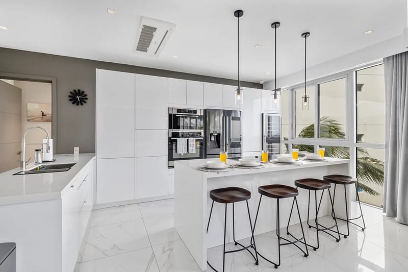 Cocina moderna con electrodomésticos, asientos en la isla y acceso a un balcón privado.