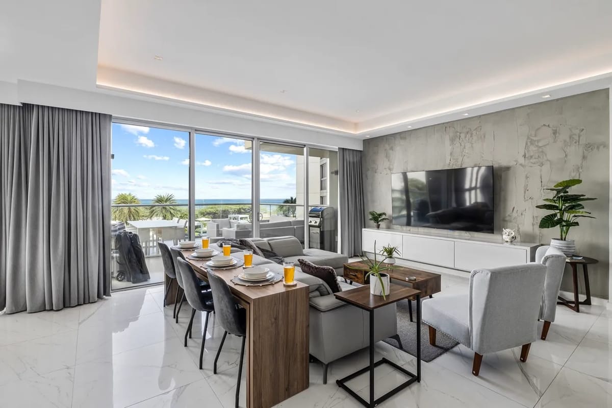 Sala de estar y comedor de concepto abierto con vistas al agua y luz natural.