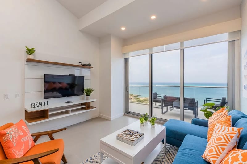Ponte cómodo en tu luminosa sala de estar con vistas a la costa a través de ventanas de piso a techo. Relájate en cómodos asientos con detalles de colores vivos mientras disfrutas del sereno mar más allá de tu terraza privada.