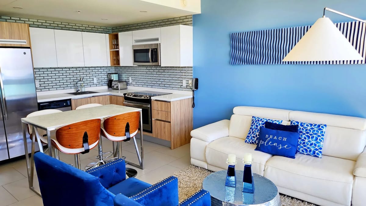 Airy open-concept living space with coastal furnishings and a fully equipped kitchen.