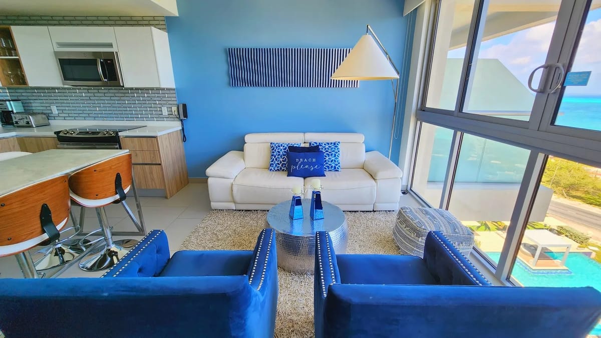 Relax in the bright, open living space with floor-to-ceiling windows, ocean views, plush seating, and a fully equipped kitchen.