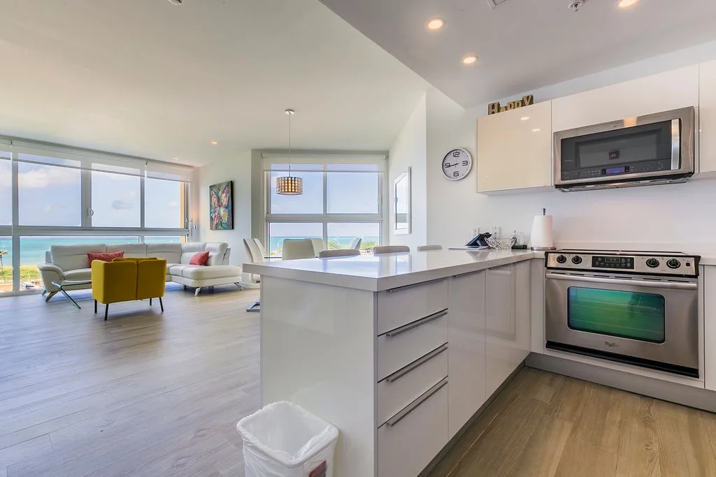 Su cocina gourmet se integra con una sala de estar bañada por el sol, donde los ventanales de piso a techo enmarcan impresionantes vistas del océano turquesa. Cocine, relájese y disfrute de la belleza costera.