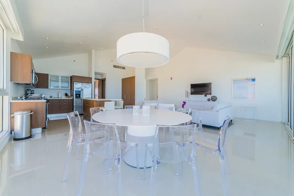 Gather around the sleek white table in the bright, open-plan space.