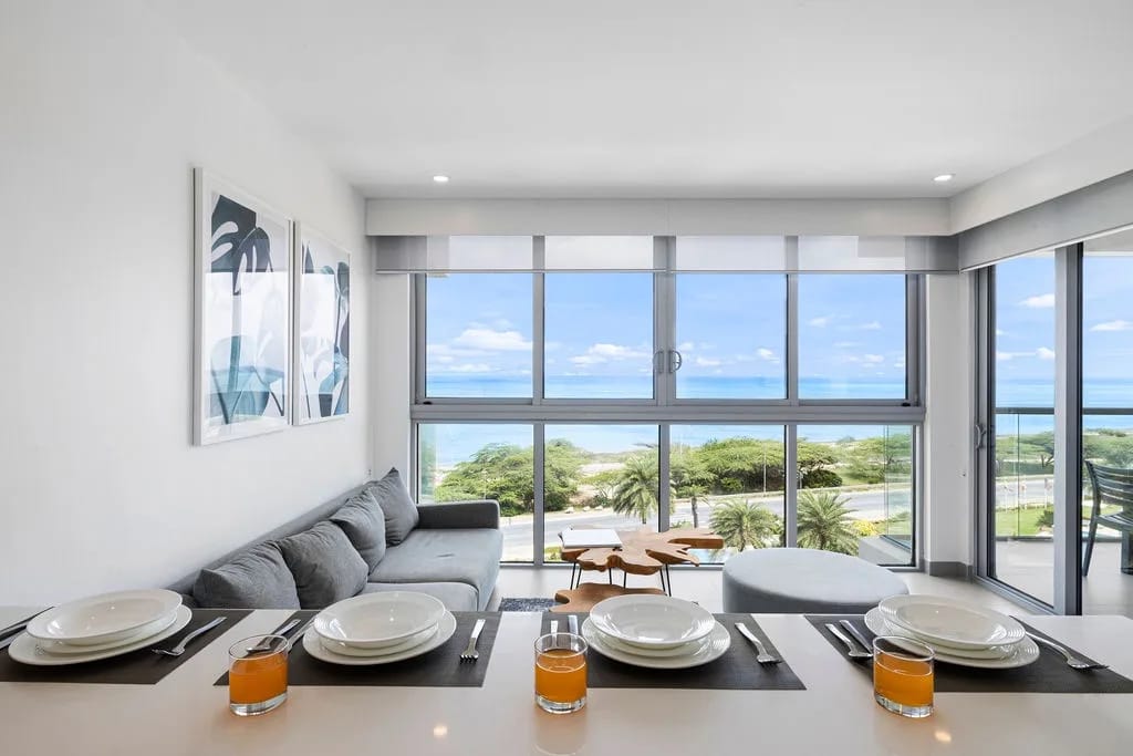 Bright, modern living and dining area with sweeping sea views. Relax on plush seating while enjoying the coastal breeze and tropical greenery just outside your windows.