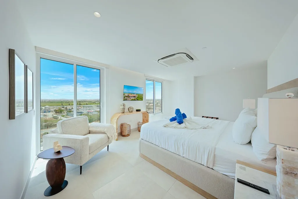 Sumérgete en la suave ropa de cama y despierta con amplias vistas del campo a través de ventanas de piso a techo que inundan tu dormitorio de luz natural.
