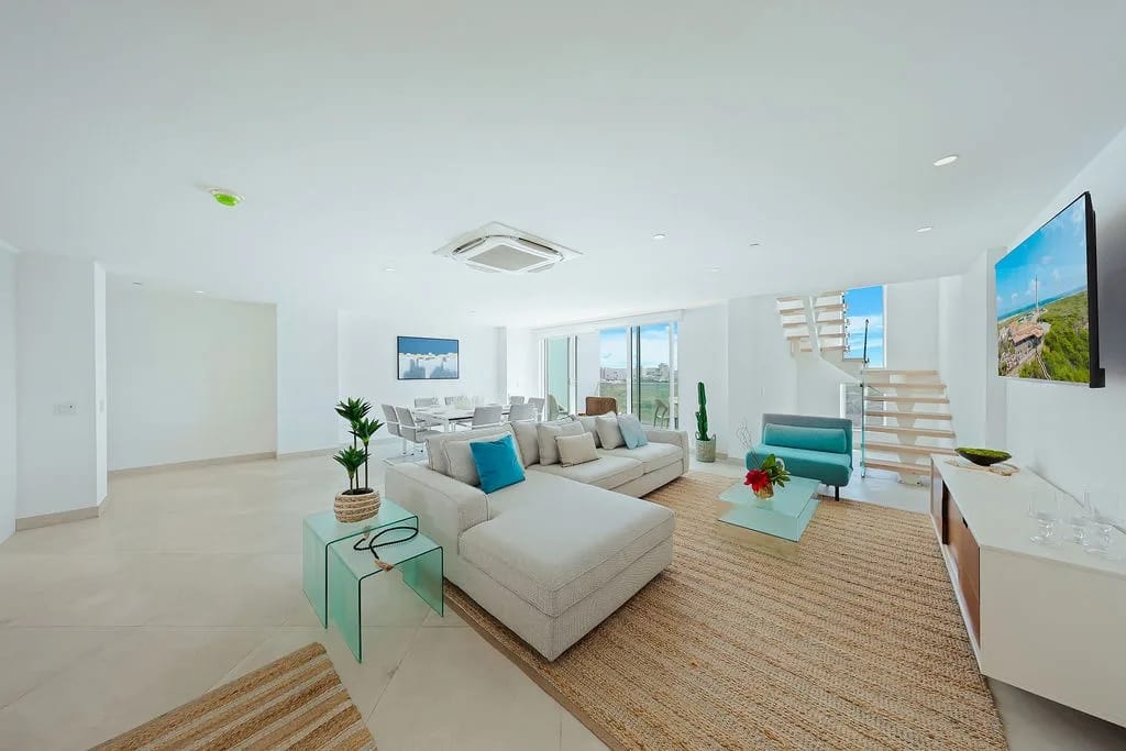 Relájate en tu amplia y luminosa sala de estar, donde el diseño elegante se combina con la comodidad costera, mientras entran las brisas del océano y se vislumbra el mar a lo lejos.