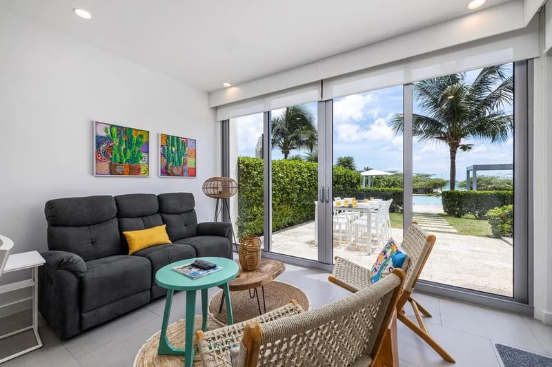 Sala de estar luminosa con vistas a la zona de la piscina a través de puertas de vidrio de piso a techo.